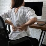 Business woman suffering from back pain in office home